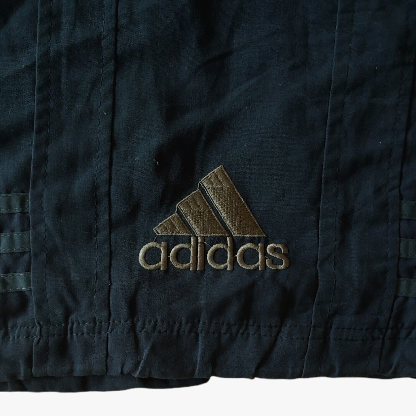Embroidered hem of vintage 90s men's Adidas Equipment navy tactical vest.