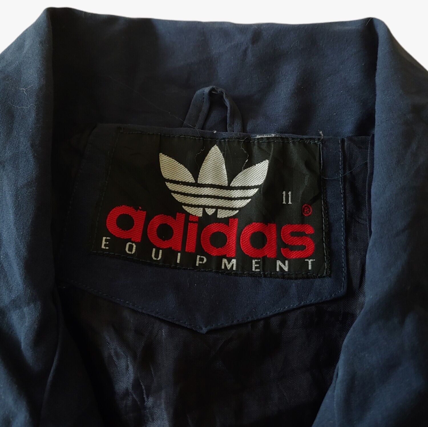 Label of vintage 90s men's Adidas Equipment navy tactical vest.