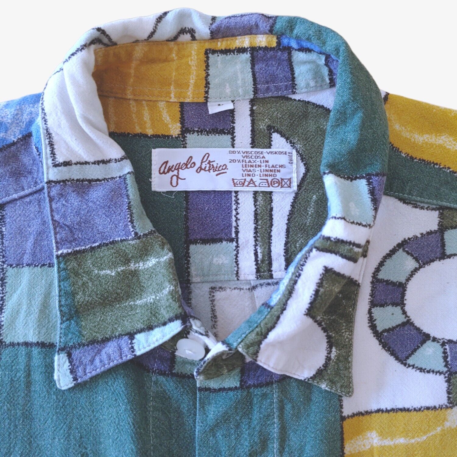 Label of vintage 90s men's Angelo Litrico short-sleeve shirt with a colourful geometric sailing boat print.