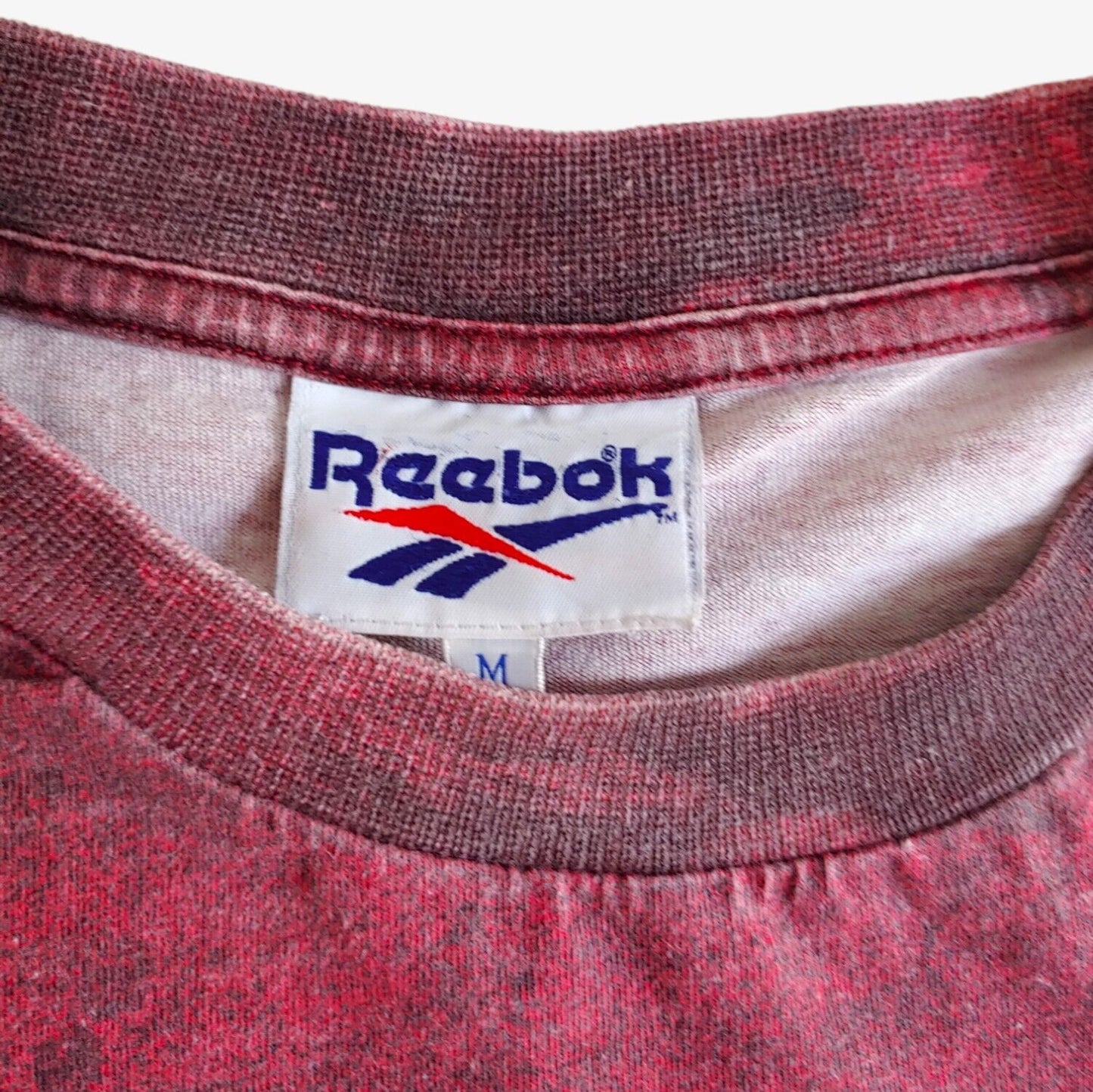 Label of vintage 90s men's Reebok tie-dye t-shirt with 'SLAM' printed in yellow bold letters on the front.