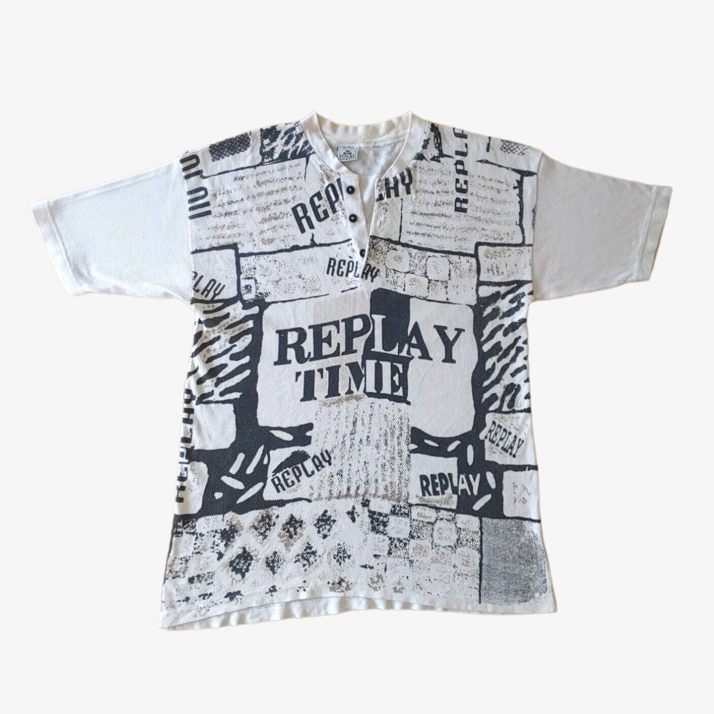 A vintage 90s men's white t-shirt with black all over print text and graphics, featuring a ribbed texture and short sleeves.